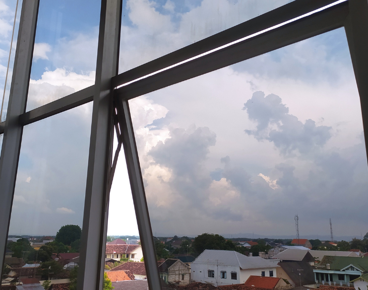 Nowoczesne okno cienkoramowe z widokiem na panoramę miasta – minimalistyczne profile aluminiowe i duże przeszklenia.